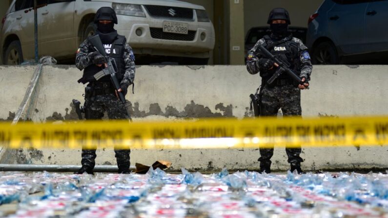 Policías antinarcóticos ecuatorianos montan guardia junto a paquetes de cocaína, en el puerto de Guayaquil, Ecuador, el 1 de abril de 2022. (Marcos Pin/AFP vía Getty Images)