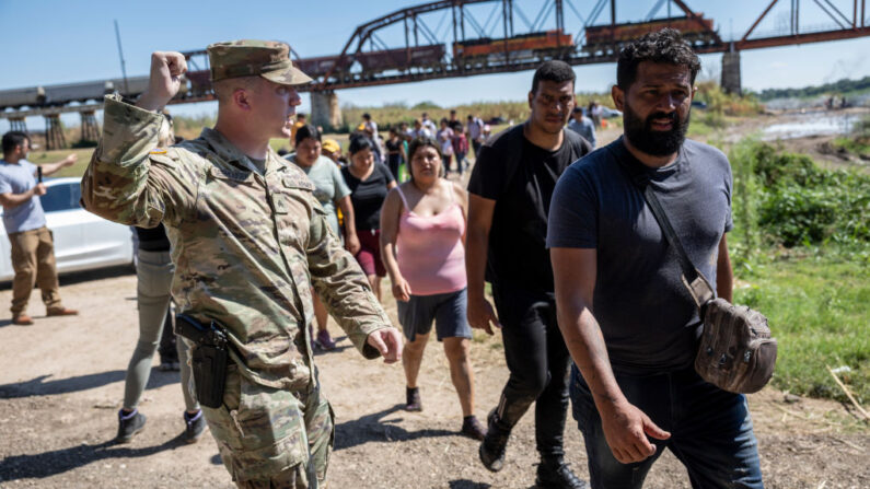 Un soldado de la Guardia Nacional de Texas dirige a los inmigrantes hacia un puesto de control de la Patrulla Fronteriza de EE. UU. después de que cruzaron la frontera entre Estados Unidos y México el 28 de septiembre de 2023 en Eagle Pass, Texas. (John Moore/Getty Images)