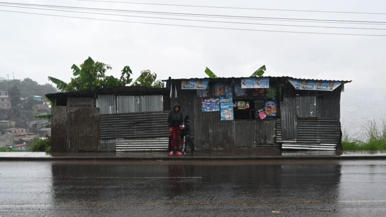 Personas de pie en una calle bajo fuertes lluvias en Tegucigalpa (Honduras), el 30 de octubre de 2023. (Orlando Sierra/AFP vía Getty Images)