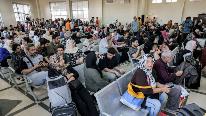Varias personas sentadas en la zona de espera del paso fronterizo de Rafah, en el sur de la Franja de Gaza, antes de cruzar a Egipto, el 1 de noviembre de 2023. (Mohammed Abed/AFP vía Getty Images)