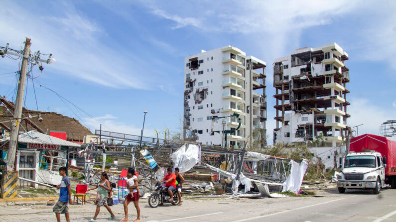 Varias personas caminan cerca de dos edificios dañados tras el paso del huracán Otis por Acapulco el 26 de octubre de 2023 en Acapulco, México. (Oscar Guerrero Ramirez/Getty Images)