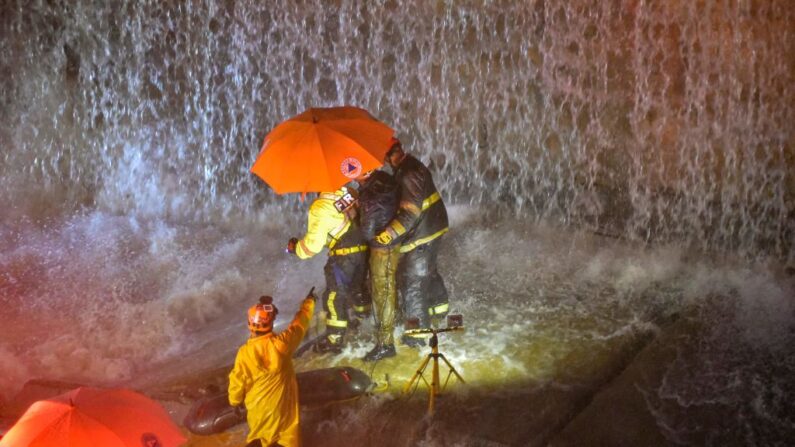 Rescatistas buscan personas atrapadas bajo un muro que colapsó sobre varios vehículos tras las fuertes lluvias en la avenida 27 de Febrero en Santo Domingo (República Dominicana) el 18 de noviembre de 2023. (Felix Leon/AFP vía Getty Images)