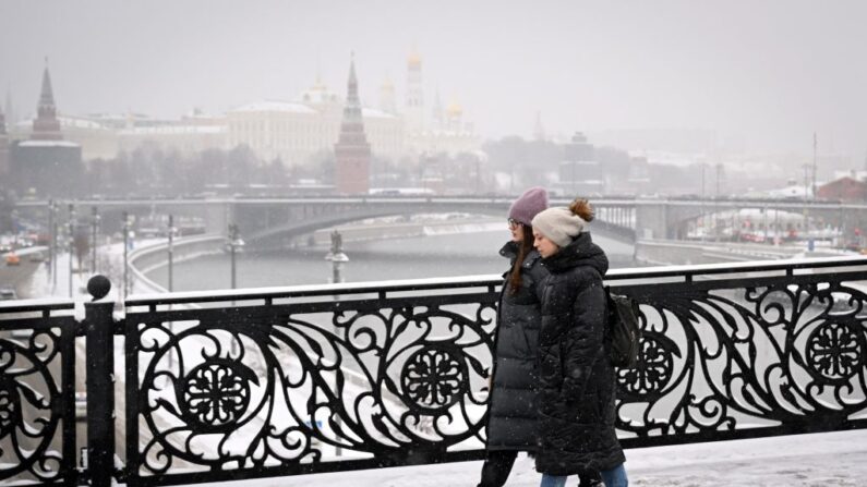 Mujeres caminan por el Puente del Patriarca sobre el río Moscova, con el Kremlin visto en la distancia, durante una nevada en Moscú (Rusia) el 24 de noviembre de 2023. (Natalia Kolesnikova/AFP vía Getty Images)