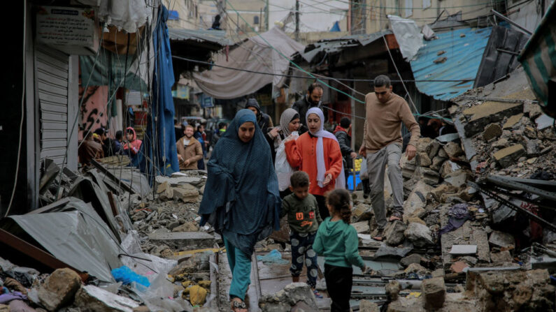 Palestinos caminan entre escombros de edificios alcanzados por ataques israelíes, cerca del mercado de Al-Zawiya, en la ciudad de Gaza, el 27 de noviembre de 2023, en el cuarto día de tregua en los combates entre Israel y Hamás. (Omar El-Qattaa/AFP vía Getty Images)