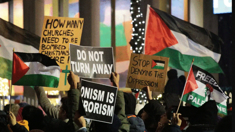 Manifestantes pro palestinos sostienen varios carteles en alto durante su manifestación frente al edificio de Fox News en la 6ª Avenida en el centro de Manhattan el 29 de noviembre de 2023. (Richard Moore/The Epoch Times)