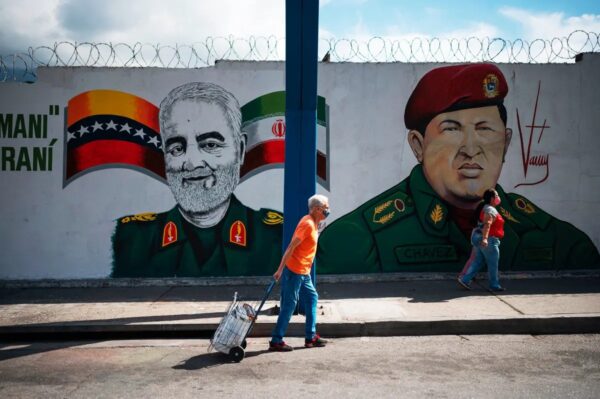 La gente camina junto a un mural que representa al general iraní asesinado Qasem Soleimani (I) junto al fallecido presidente venezolano Hugo Chávez (D), en Caracas, Venezuela, el 4 de enero de 2023. (FEDERICO PARRA/AFP vía Getty Images)