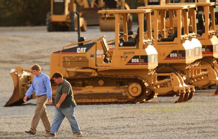 Una foto de archivo de dos hombres caminando cerca de filas de productos Caterpillar en Quinn Co. Caterpillar el 26 de enero de 2009 en City of Industry, California. (David McNew/Getty Images)