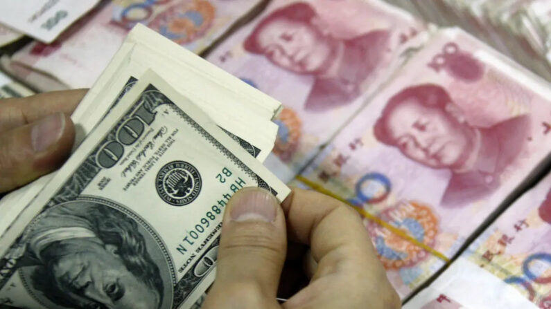 Billetes de dólar estadounidense se contaban junto a pilas de billetes de 100 yuanes (RMB) en un banco de Huaibei, en la provincia oriental china de Anhui, el 24 de septiembre de 2013.(STR/AFP via Getty Images)
