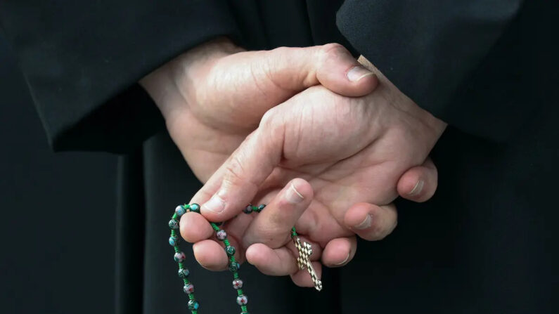 Un hombre sostiene las cuentas de un rosario en el exterior de una iglesia católica estadounidense. (Rob Carr/Getty Images)