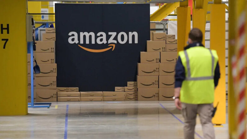 Un empleado del gigante estadounidense Amazon pasa junto a su logotipo el día de la inauguración del nuevo centro de distribución en Augny, al este de Francia, el 23 de septiembre de 2021. (SEBASTIEN BOZON/AFP vía Getty Images)