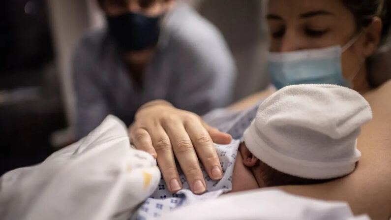 Un padre y una madre miran a su hijo recién nacido en la maternidad del hospital Diaconesses de París, el 17 de noviembre de 2020. (Martin Bureau/AFP vía Getty Images)