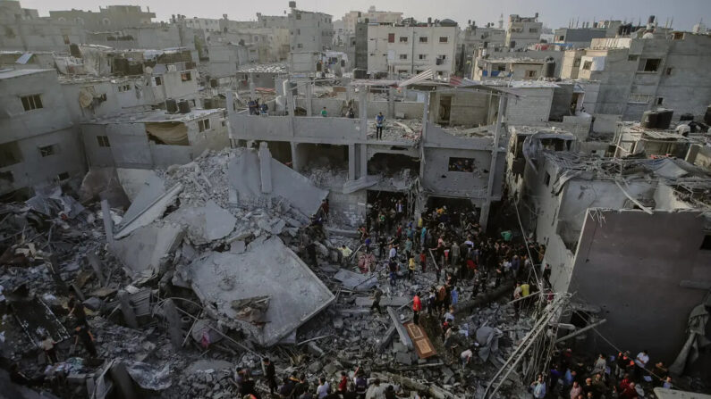 Civiles palestinos y equipos de rescate revisando los escombros de un edificio derrumbado en Al-Maghazi, ubicado en el centro de la Franja de Gaza, en busca de sobrevivientes y víctimas tras el bombardeo israelí del 5 de noviembre de 2023. (Mohammed Zaanoun/Middle East Images/ AFP vía Getty Images)
