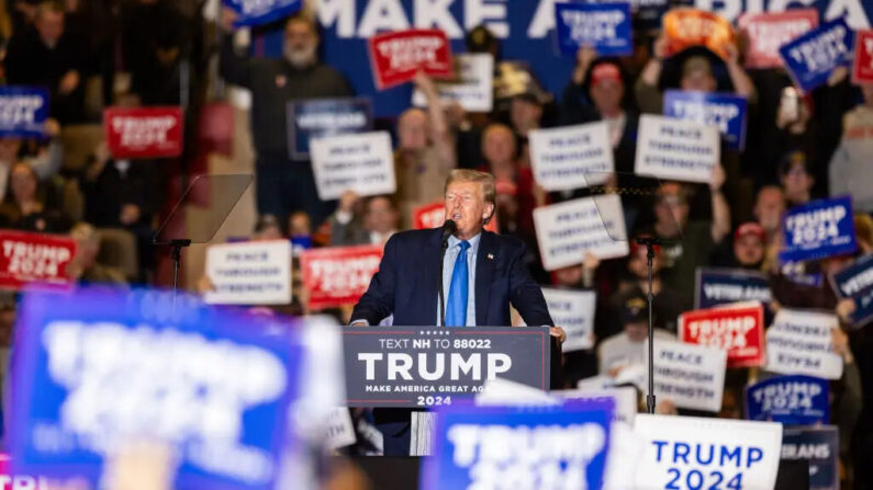 Un partidario del ex presidente republicano Donald Trump sostiene carteles mientras él pronuncia un discurso durante un acto de campaña en Claremont, N.H., el 11 de noviembre de 2023. (Scott Eisen/Getty Images)