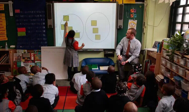 El profesor Shawn Abernathy (dcha.) enseña conceptos matemáticos utilizando una moderna pizarra de proyección informática en Harlem Success Academy, una escuela pública gratuita autónoma de enseñanza primaria del barrio de Harlem, en Nueva York. (Chris Hondros/Getty Images)