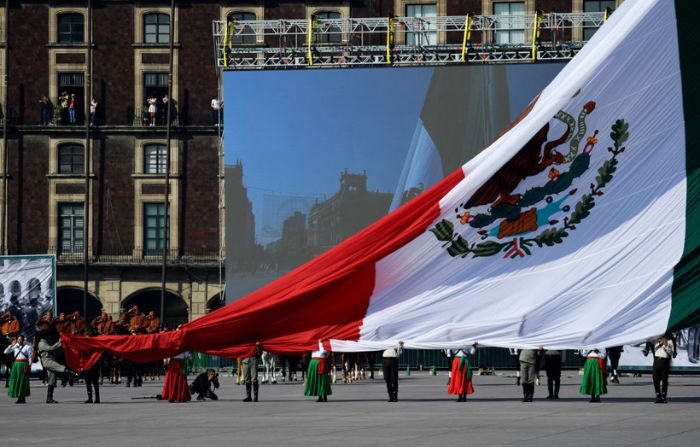 Participantes sostienen una enorme bandera mexicana durante un desfile para conmemorar el 113 aniversario de la Revolución Mexicana, en la Plaza del Zócalo en la Ciudad de México, el 20 de noviembre de 2021. (CLAUDIO CRUZ/AFP vía Getty Images)