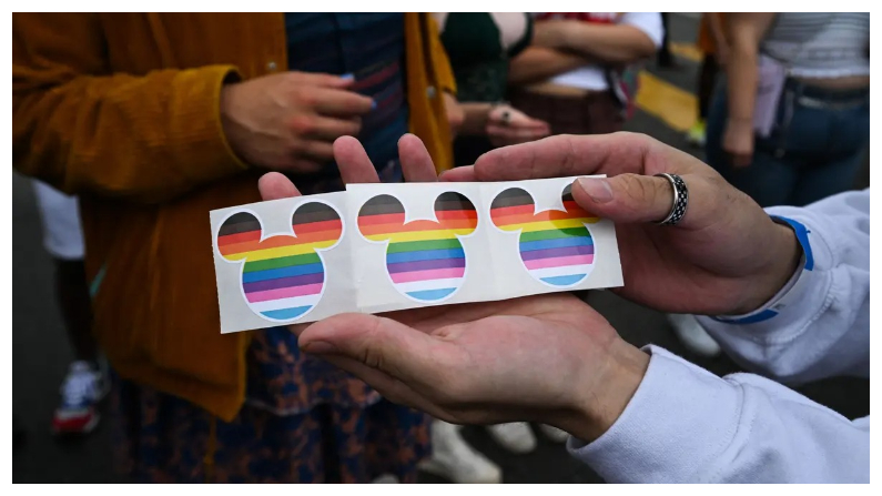 El personal de Disney ofrece a los espectadores pegatinas de las orejas de Mickey Mouse con los colores del arco iris en el desfile del Orgullo Gay de Los Ángeles de 2023 en Hollywood, California, el 11 de junio del 2023. (Robyn Beck/AFP vía Getty Images)