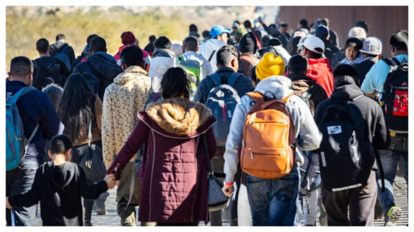 Inmigrantes ilegales que atravesaron una brecha en el muro fronterizo de Estados Unidos esperan ser procesados por agentes de la Patrulla Fronteriza en Jacumba, California, el 7 de diciembre del 2023. (John Fredricks/The Epoch Times)