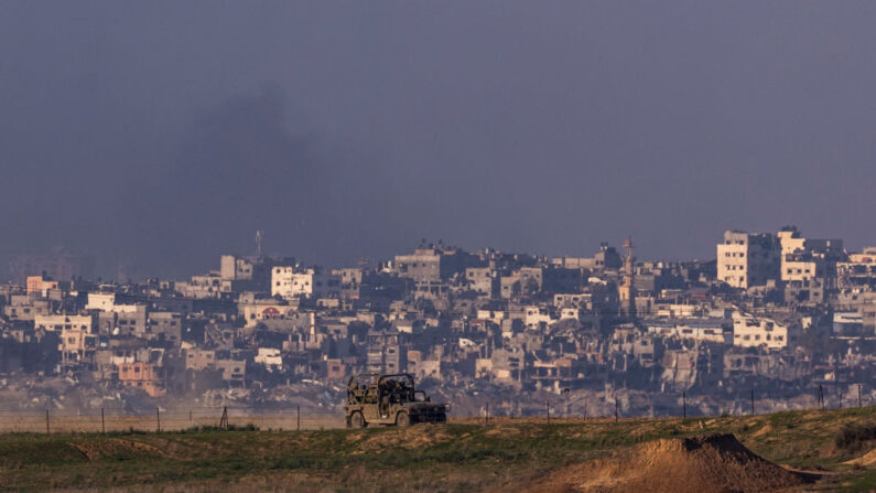 Un vehículo militar pasa mientras sale humo del norte de Gaza visto desde el lado israelí de la frontera el 19 de diciembre de 2023 en el sur de Israel. (Maja Hitij/Getty Images)
