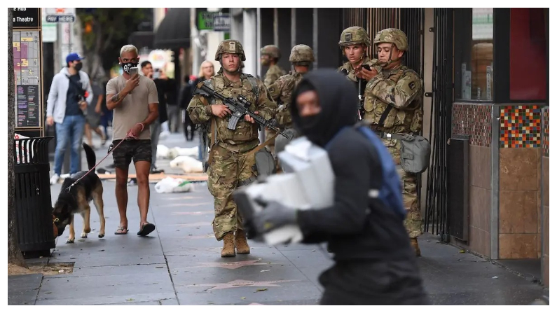 Un presunto saqueador que lleva cajas de zapatos pasa corriendo junto a soldados de la Guardia Nacional en la zona de Hollywood, en Los Ángeles, el 1 de junio del 2020. (Robyn Beck/AFP vía Getty Images)