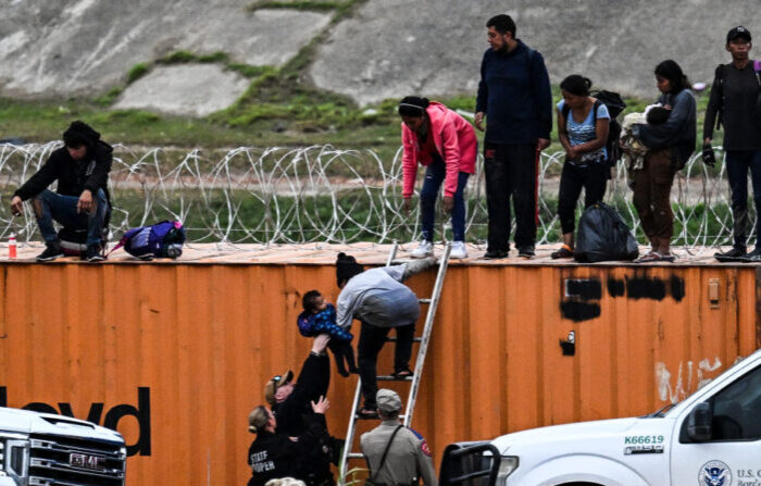 Los agentes de Aduanas y Protección Fronteriza le quitan a su madre a un niño inmigrante después de cruzar la frontera desde México en Eagle Pass, Texas, el 22 de diciembre de 2023. (CHANDAN KHANNA/AFP via Getty Images)