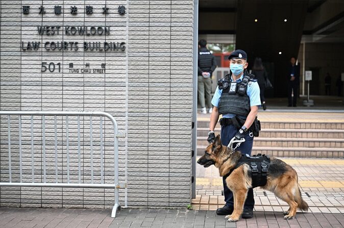 Un perro policía y su adiestrador frente a la entrada del tribunal de West Kowloon para el día de apertura del juicio del magnate de los medios de comunicación pro-democracia Jimmy Lai en Hong Kong el 18 de diciembre de 2023. (PETER PARKS/AFP vía Getty Images)