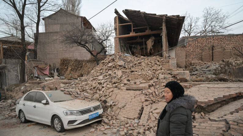 Una mujer pasa junto a una casa derrumbada en Dahejia, en el condado de Jishishan, en la provincia noroccidental china de Gansu, el 20 de diciembre de 2023. (Pedro Pardo/AFP vía Getty Images)