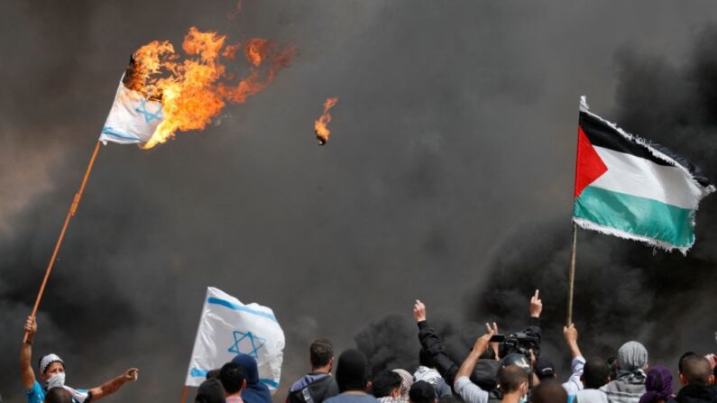 Manifestantes palestinos queman banderas israelíes cerca de la valla fronteriza con Israel, al este de Khan Yunis, en el sur de la ciudad de Gaza, el 13 de abril de 2018. (THOMAS COEX/AFP vía Getty Images)