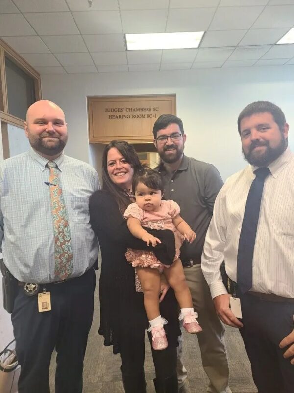 Angel Grace con sus padres adoptivos en el Feliz Día del Recibimiento. (Cortesía de la Oficina del Sheriff del Condado de Polk)