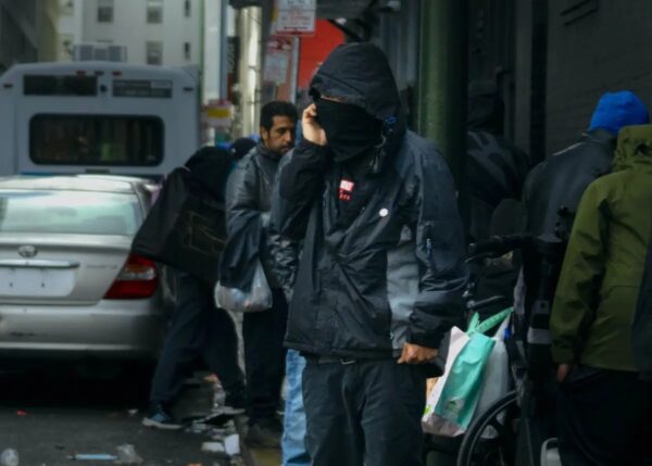 Un presunto traficante de drogas cerca de una fila de drogadictos en San Francisco, California, el 23 de febrero del 2023. (John Fredricks/The Epoch Times)