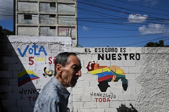 Un hombre camina junto a un mural que hace campaña a favor de un referéndum para pedir a los venezolanos que consideren la anexión de la región de Essequibo, administrada por Guyana, en Caracas, Venezuela, el 28 de noviembre de 2023. (Federico Parra/AFP vía Getty Images)