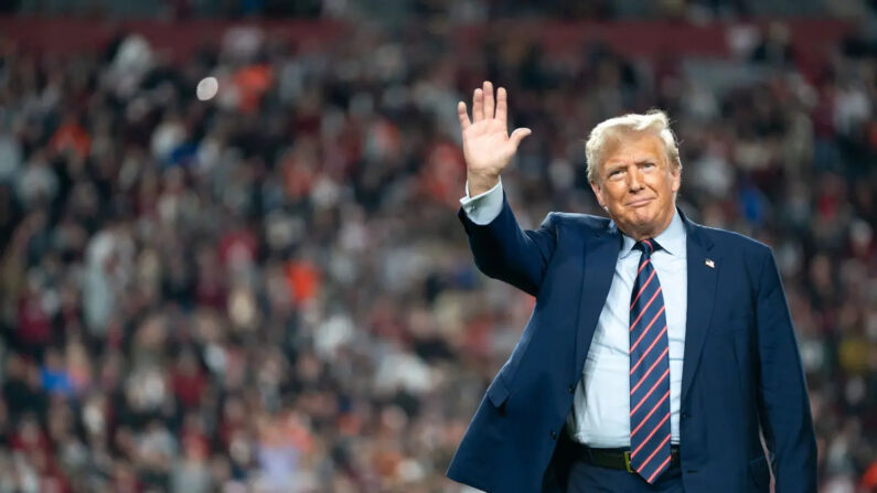 El expresidente Donald Trump saluda a los aficionados al fútbol americano en el campo durante el descanso de la Palmetto Bowl entre Clemson y Carolina del Sur en el estadio Williams Brice de Columbia, Carolina del Sur, el 25 de noviembre de 2023. (Sean Rayford/Getty Images)