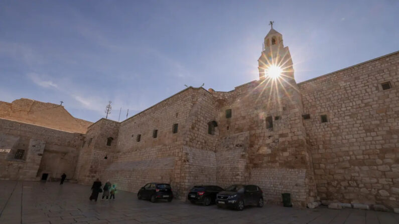 Palestinos caminan por la plaza vacía frente a la Iglesia de la Natividad en la ciudad bíblica de Belén, el 20 de diciembre de 2023, antes de Navidad en medio de los combates en curso entre Israel y el grupo terrorista palestino Hamás en la Franja de Gaza. (Hazem Bader/AFP vía Getty Images)