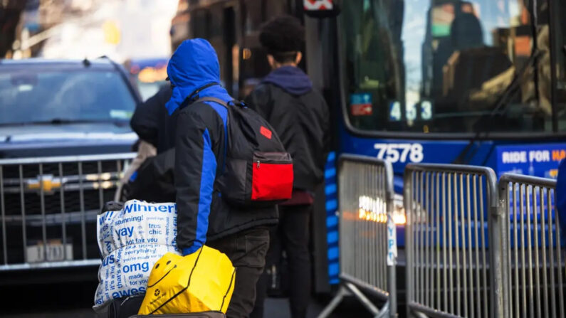 Inmigrantes ilegales llevan sus pertenencias a un autobús tras aceptar ser realojados después de ser desalojados del Hotel Watson en Nueva York el 30 de enero de 2023. (Michael M. Santiago/Getty Images)