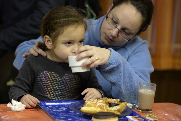 Una mujer y una niña desayunan en un comedor social de Barcelona el 17 de diciembre de 2013. Desde hace tres años, el comedor social sirve desayunos calientes a los más necesitados. A diferencia de la mayor parte de la economía española, está experimentando una gran demanda.
  (LLUIS GENE/AFP vía Getty Images)