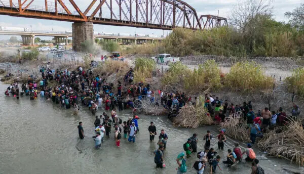 Migrantes esperan en el Río Grande para que les abran una abertura en una barrera de alambre de púas, para cruzar a Estados Unidos, en Eagle Pass, Texas, el 25 de septiembre de 2023. (Andrew Caballero-Reynolds/AFP vía Getty Images)
