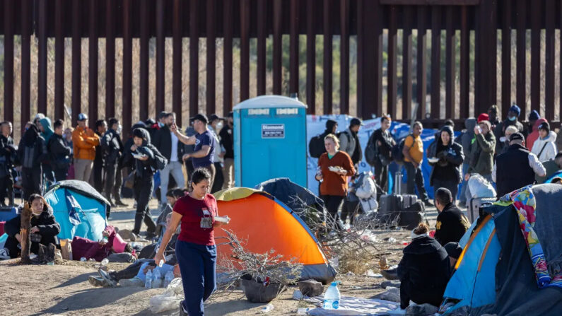 Inmigrantes ilegales que pasaron por una brecha en el muro fronterizo de EE.UU. esperan ser procesados por agentes de la Patrulla Fronteriza en Jacumba, California, el 7 de diciembre de 2023. (John Fredricks/The Epoch Times)