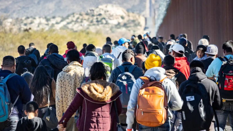Migrantes que pasaron por una brecha en el muro fronterizo de Estados Unidos esperan ser procesados por agentes de la Patrulla Fronteriza en Jacumba, California, el 7 de diciembre de 2023. (John Fredricks/The Epoch Times)