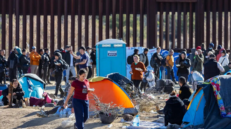 Inmigrantes ilegales que pasaron por una brecha en el muro fronterizo de Estados Unidos esperan ser procesados por agentes de la Patrulla Fronteriza en Jacumba, California, el 7 de diciembre de 2023. (John Fredricks/The Epoch Times)