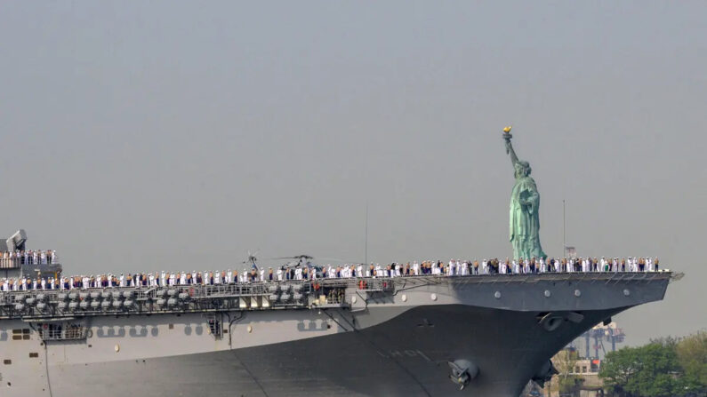 Marineros e infantes de marina estadounidenses en la cubierta de vuelo del USS Bataan, un buque de asalto anfibio de clase Wasp, a su paso por la Estatua de la Libertad durante la Semana de la Flota en el puerto de Nueva York el 24 de mayo de 2023. (Angela Weiss/AFP vía Getty Images)