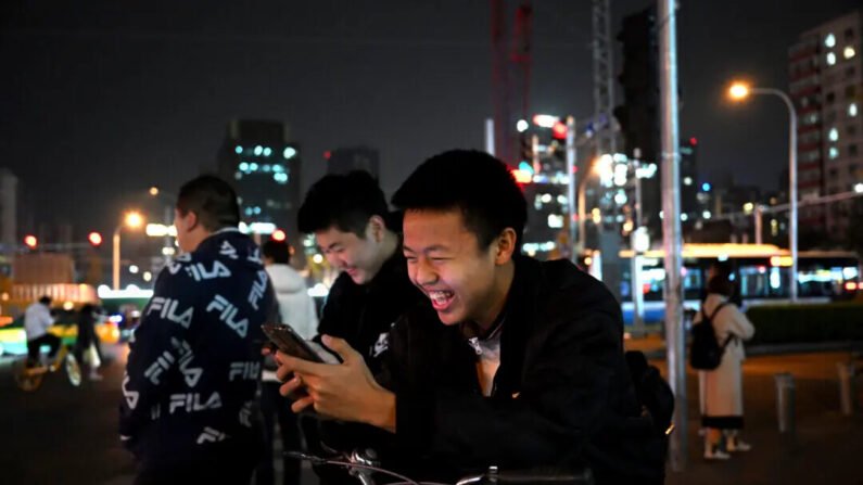 Los estudiantes juegan videojuegos en sus teléfonos mientras esperan en una intersección durante la hora pico, en Beijing, China, el 15 de noviembre de 2023. (Kevin Frayer/Getty Images)
