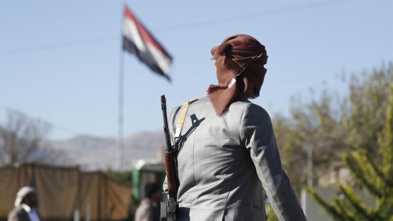 Un combatiente hutí armado pasa junto a una bandera yemení que ondea en un santuario de los combatientes hutíes asesinados, en Saná (Yemen), el 17 de enero de 2024. EFE/EPA/Yahya Arhab