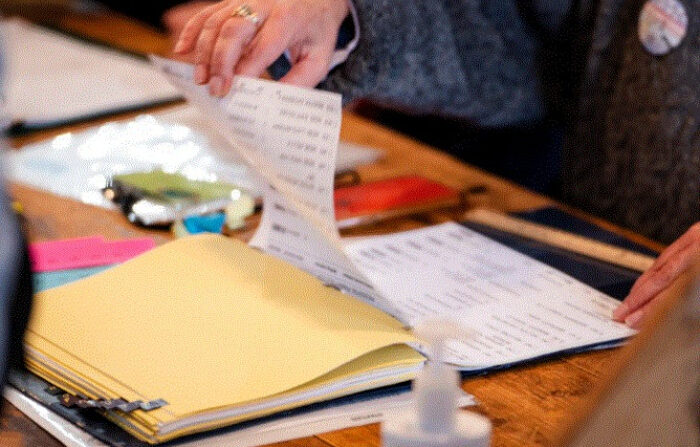 Un trabajador electoral revisa la lista de votantes registrados en un sitio de votación en el Ayuntamiento de Sanbornton en Sanbornton, Nuevo Hampshire, el 23 de enero de 2024. (Madalina Vasiliu/The Epoch Times)
