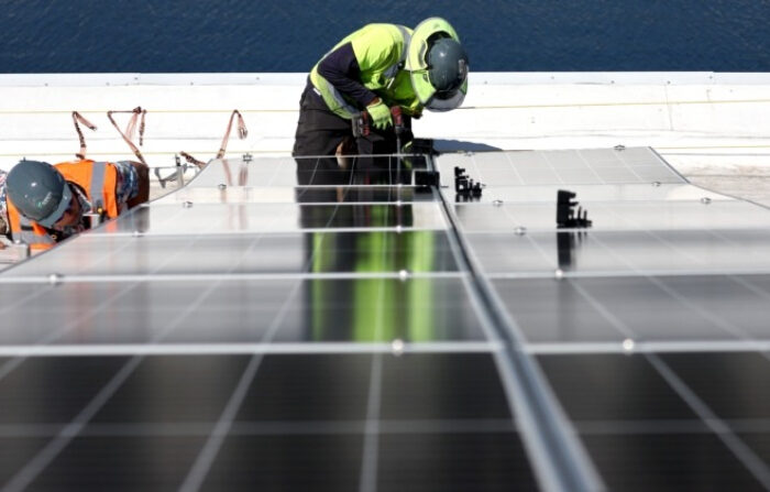 Trabajadores instalan paneles solares durante la fase de finalización de una cubierta solar de 4 acres sobre las instalaciones de investigación y desarrollo de AltaSea en el Puerto de Los Ángeles en Los Ángeles, California, el 21 de abril de 2023. (Mario Tama/Getty Images)