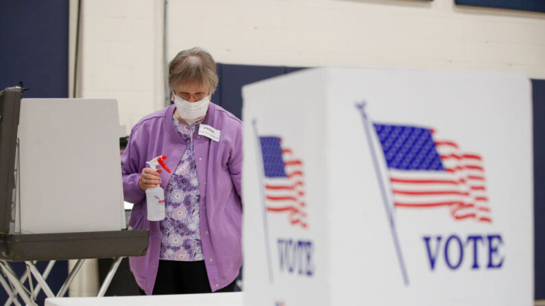 Un observador electoral limpia las cabinas de votación durante las elecciones primarias presidenciales demócratas en el gimnasio de la Iglesia Bíblica de Kenosha, en Kenosha, Wisconsin, el 7 de abril de 2020.(KAMIL KRZACZYNSKI/AFP vía Getty Images)