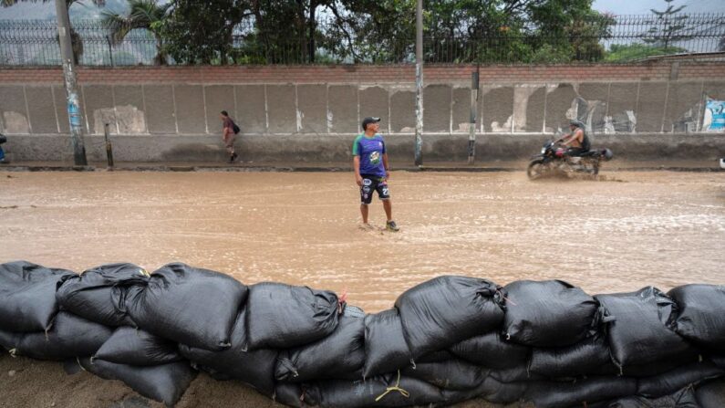 Personas vadean el agua que inunda la principal carretera de acceso de Lima al interior del país en los Andes tras las fuertes lluvias en Chaclacayo, al este de Lima, Perú, el 15 de marzo de 2023. (Cris Bouroncle/AFP vía Getty Images)