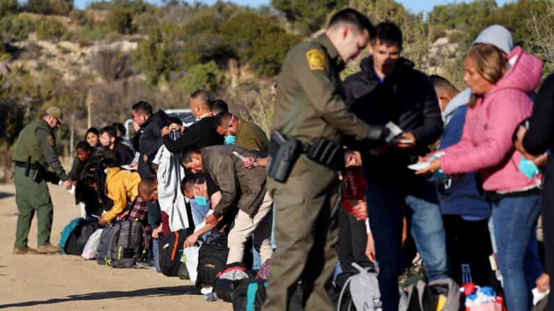 Agentes de la Patrulla Fronteriza de EE. UU. verifican los documentos de identificación de los migrantes que buscan asilo antes de ser transportados a un centro de procesamiento de la Patrulla Fronteriza en Jacumba Hot Springs, California, el 1 de diciembre de 2023. (Mario Tama/Getty Images)