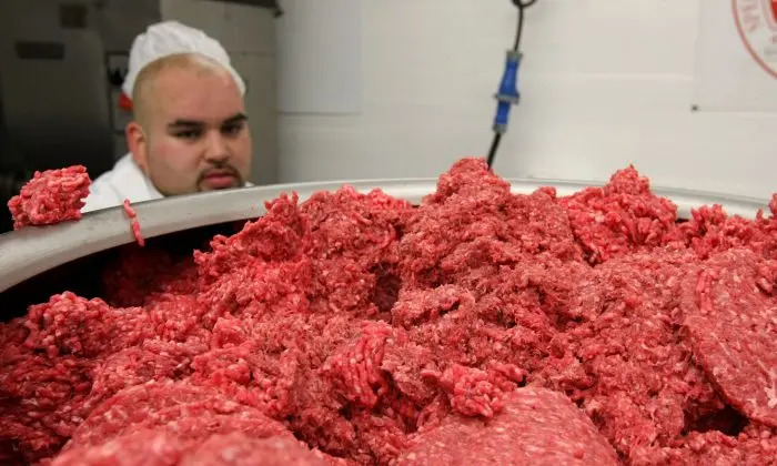 Foto de archivo que muestra a un trabajador de una planta de envasado de carne controlando la carne molida mientras pasa por una máquina que hace hamburguesas en San Francisco, California, el 24 de junio de 2008. (Justin Sullivan/Getty Images)