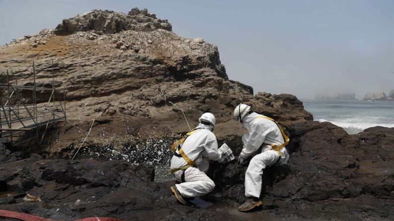 Personal limpia con disolvente rocas con restos de petroleo en la playa Cavero en el distrito de Ventanilla en Lima (Perú). EFE/Paolo Aguilar