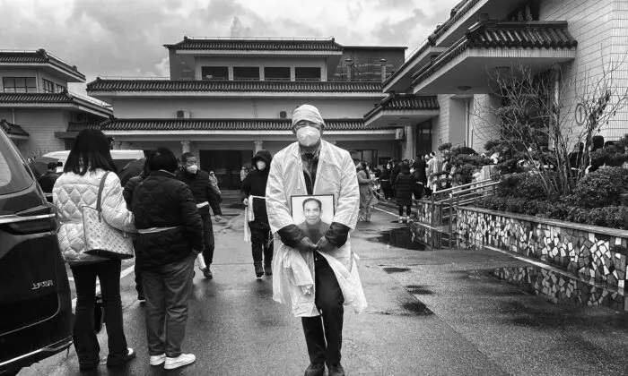 Un doliente lleva una foto de un ser querido mientras viste ropa funeraria blanca tradicional en una funeraria en Shanghai, China, el 14 de enero de 2023. (Kevin Frayer/Getty Images)