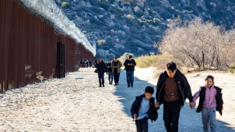 Migrantes caminan por el lado estadounidense del muro fronterizo de Estados Unidos tras cruzar por una brecha abierta en Jacoumba, California, el 6 de diciembre de 2023. (John Fredricks/The Epoch Times)
